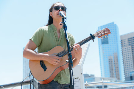 young latin man with long hair and busker glasses guitarist in Buenos Aires, working making art and...