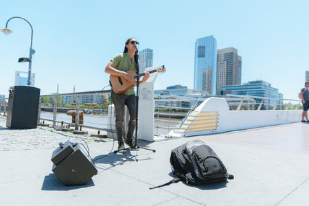 front view of young man with long dark hair with sunglasses busker Venezuelan guitarist playing and...