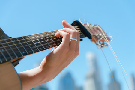 Close-up of hands on guitar neck of man guitarist making chord playing making music on street making...