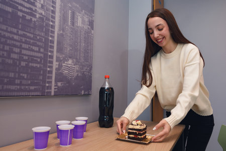 Happy young Woman is smiling while taking cake from table to go sing happy birthday in business...