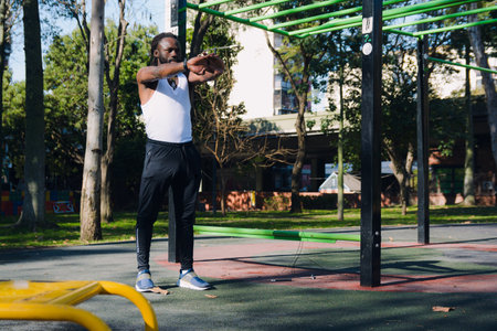 Black Man with dreadlocks and beard wearing sleeveless shirt and black jogging pants standing in the...