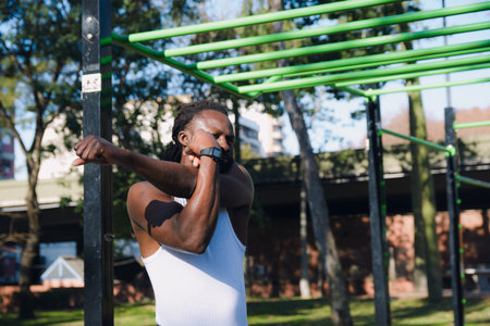 Young African Man with dreadlocks and beard wearing a sleeveless t-shirt is demonstrating how to do...