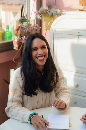 Vertical image for social media of a Woman at home sitting drawing and smiling very happy, she has long black hair and is wearing a white sweater, lifestyle concept with copy space.の写真素材