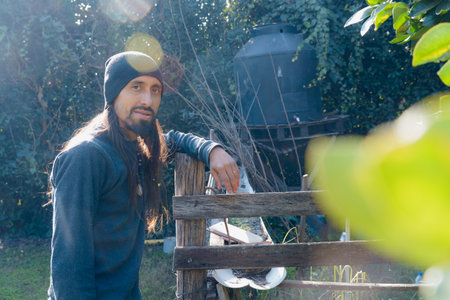 Portrait of adult Latino male farmer, smiling and looking at the camera happily with one hand on the...