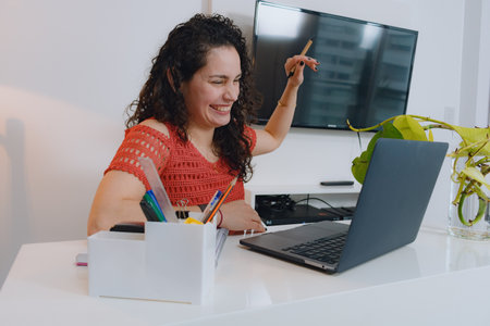 Happy young latin Woman streaming on social media with laptop, she is smiling while talking to her...