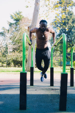 Vertical image for social media of outdoor exercises, black man doing calisthenics shirtless in the...