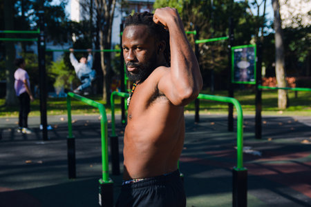Side view of black Man with dreadlocks and beard looking at camera posing showing his strength, he...