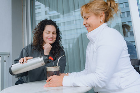 Women mother and daughter sitting in the apartment relaxed drinking mate, sharing with each other happy and calm.の写真素材