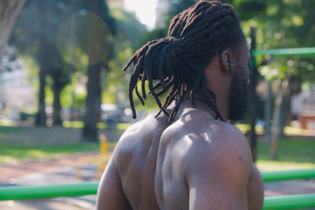 Back view of muscular black man with dreadlocks and shirtless while doing calisthenics exercise in park, fitness and sport concept, copy spaceの写真素材