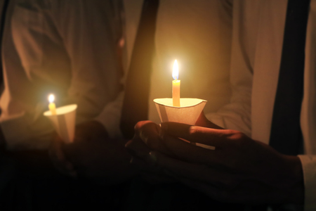 Closeup hand holding candles in paper cup with light pray and hope concept background.の写真素材