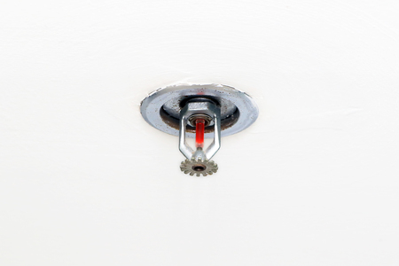 Fire sprinkler with vakuum sealed glass tube installed in the ceiling office building. Fire protection system equipment isolated in white background.の写真素材