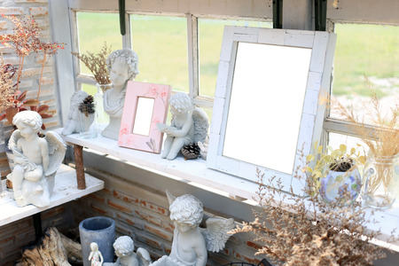 Shabby chic interior decor for farmhouse with empty photo frame and little angle statue.の写真素材
