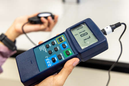 Hand holding Digital handheld light lux meter intensity of light with photodiode sensor LDR Photometer for measure the overall illuminance of an indoor or outdoor area.の写真素材