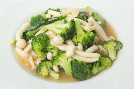 fried broccoli and shimeji mushroom in oyster sauce on white backgroundの写真素材