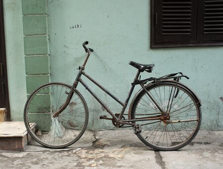 Black vintage bicycle leaning against a grunge wallの写真素材