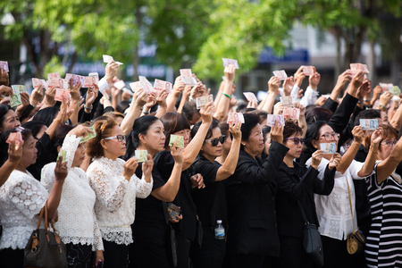 SURATTHANI, THAILAND - OCTOBER 16 : Crowds of mourners hold Thai cash for show picture of King Bhumibol during mourning ceremony at Suratthani City Hall on October 16, 2016 in Suratthani, Thailand.のeditorial素材