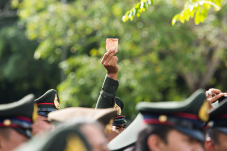 SURATTHANI, THAILAND - OCTOBER 16 : Crowds of mourners hold Thai cash for show picture of King Bhumibol during mourning ceremony at Suratthani City Hall on October 16, 2016 in Suratthani, Thailand.のeditorial素材