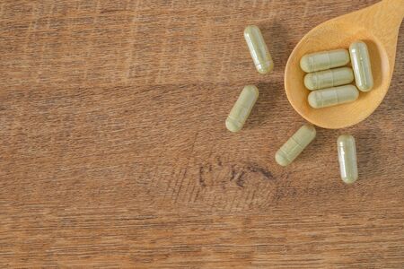 Herbal Medicine capsules in wooden spoon on wooden table. Organic Natural raw materials are good for health lifestyle and healthcare. Top viewの写真素材