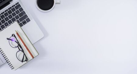 Flat lay, White office desk with laptop, empty notebook, pencil, black coffee cup and eyeglasses....