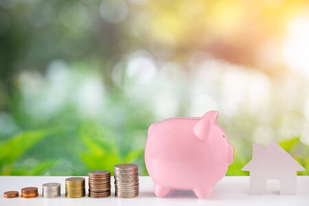 Piggybank of money with coins stack stair step up growing saving money for house with green nature and bokeh background. Dividend of bank deposit and stock investment concept. with blank copyの写真素材