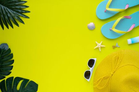 Summer holiday of traveler women. Top view from above of beach accessories and a hat with sunglasses and sandals on yellow background. Flat lay with copy space. Tropical fashion vacation concept.の写真素材