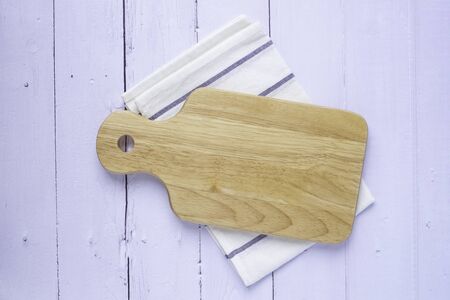 Top view above of Wooden chopping board with napkin on white table background. Wood Cutting board with handle and hole for hanging. Empty utensil with copy space.の写真素材