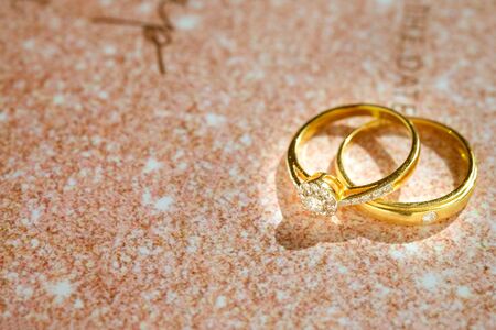 Close up of Gold wedding rings or engagement rings on wedding invitation card background. Couple...
