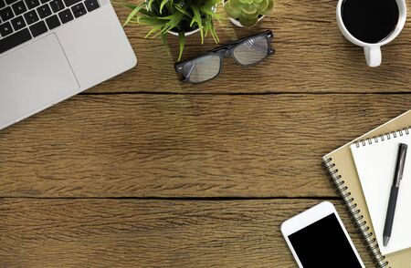 Workplace at home with wood table. Top view from above of laptop with notebook and coffee. Office space for modern creative work of designer. Flat lay with blank copy space. Business-finance concept.の写真素材