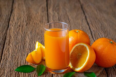 Close-up of Glass squeezed orange juice and fresh fruits ripe cut half, slice with green leaves on old wood vintage table. Breakfast food or beverage for the morning. Concept organic healthy natural.の写真素材