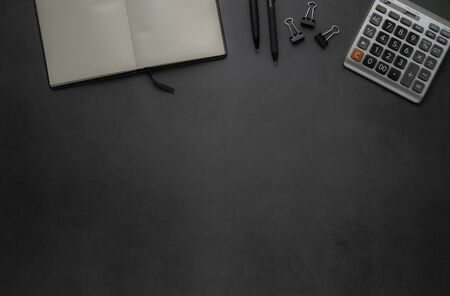 Workplace office with dark grey desk. Top view from above of Empty open notebook with calculator and...