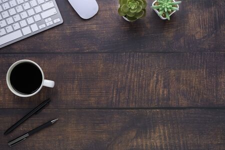Workspace in office with wood table. Top view from above of keyboard with notebook and coffee. Desk...