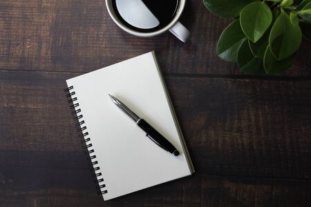 Top view from above of Blank open notebook and coffee on wood table background. Workplace for the creative work of designer at home. Flat lay, Business-finance or education concept with copy space.の写真素材