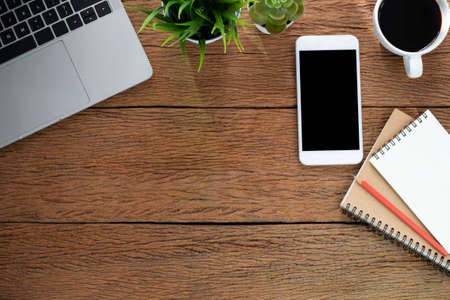 Top view above of Wood office desk table with laptop, notebook and phone with equipment other office supplies. Business and finance concept. Workplace, Flat lay with blank copy space.の写真素材