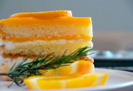 Close-up of Orange cake pie baked with orange topping and orange slices with rosemary leaf decorate...