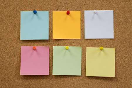Colorful reminder sticky notes push pins on cork board. empty free space.の写真素材