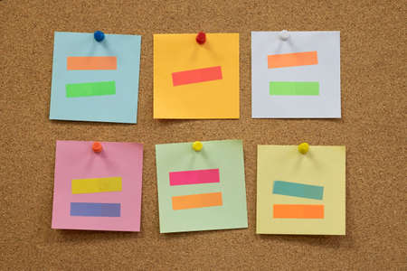Colorful reminder sticky notes push pins on cork board. empty free space.