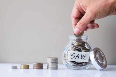 Business investment and finance accounting concept. Hand putting coin into a glass bottle with money coins stack step up growing growth. Saving money for buying a new house.の写真素材
