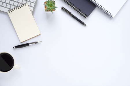 Top view above of White office desk table with keyboard, notebook and coffee cup with equipment...