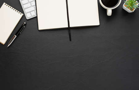 Top view of Black leather office desk table with keyboard and blank open notebook, coffee with equipment other office supplies. Business and finance concept. Workplace, Flat lay with blank copy space.の写真素材