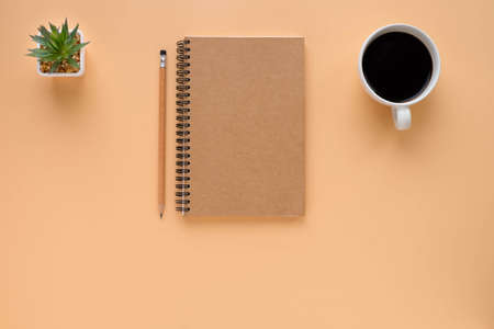 Top view above of brown spiral notebook and pencil with coffee cup isolated on brown background for design a mockup. Education and business concept. flat layの写真素材