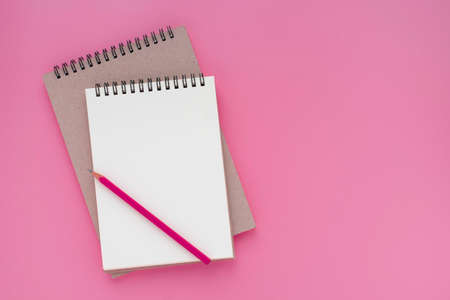Top view above of open white blank spiral notebook and pink pencil isolated on pink background for design a mockup. Education and business concept. flat layの写真素材