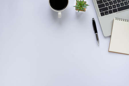 Workplace in office with white desk. Top view from above of laptop, book and coffee cup. Space for...