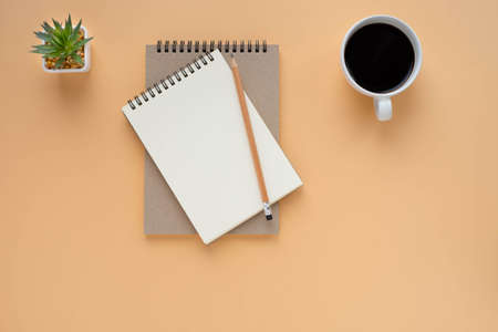 Top view of open school notebook with blank pages and pencil with coffee cup on brown background....