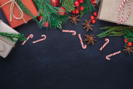 Top view above of Christmas holiday background. Composition with fir pine branches, cane, gift kraft boxes decorations on black background. Winter, Christmas, new year concept. Flat lay with copy space.の写真素材