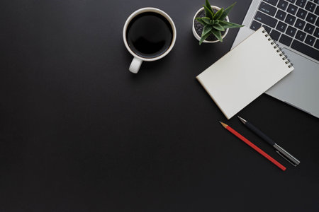 Top view above of Black office desk table with keyboard of laptop and notebook with equipment other...