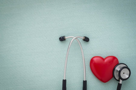 Black stethoscope with red heart of doctor for check up on light green background. Stethoscope equipment of medical use to diagnose hear sound. Health care and cardiology concept with copy.の写真素材