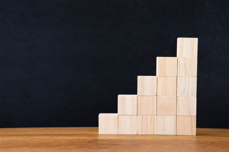 Arranging wood blocks stack as step stair on wooden table background. Business investment and...