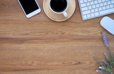 Top view above of Wooden office desk table with keyboard, coffee cup and notebook, phone with...