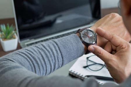 Close-up image of fashion luxury brown watch on wrist of man. Businessman working with laptop on...
