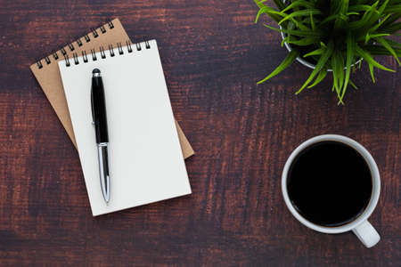 Top view of open school notebook with blank pages, coffee cup and pen for taking write notes on wood...